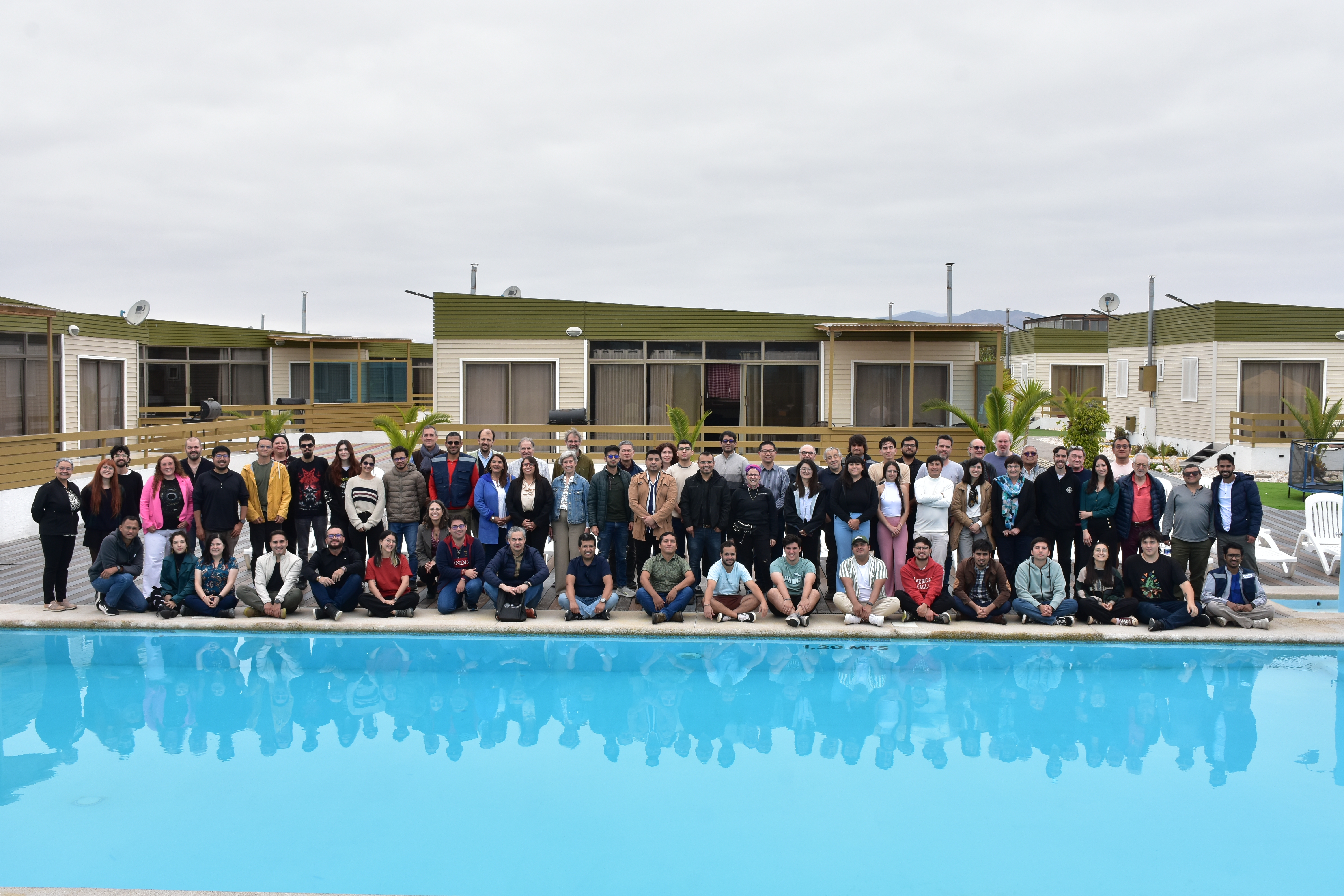 Foto panorámica del grupo que asistió a reunión de ADeLA@Atacama 2025. Cielo nublado arriba y en el lado inferior una piscina