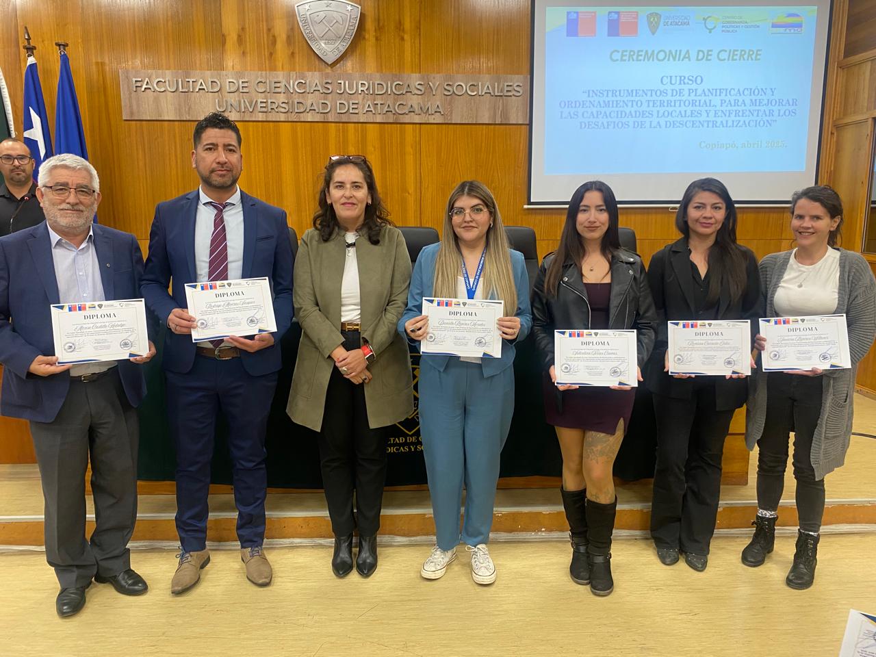 Siete personas frente a un letrero que dice Facultad de Ciencias Jurídicas y Sociales Universidad de Atacama, seis sosteniendo diplomas. Autoridad presente del Estado del Ceará