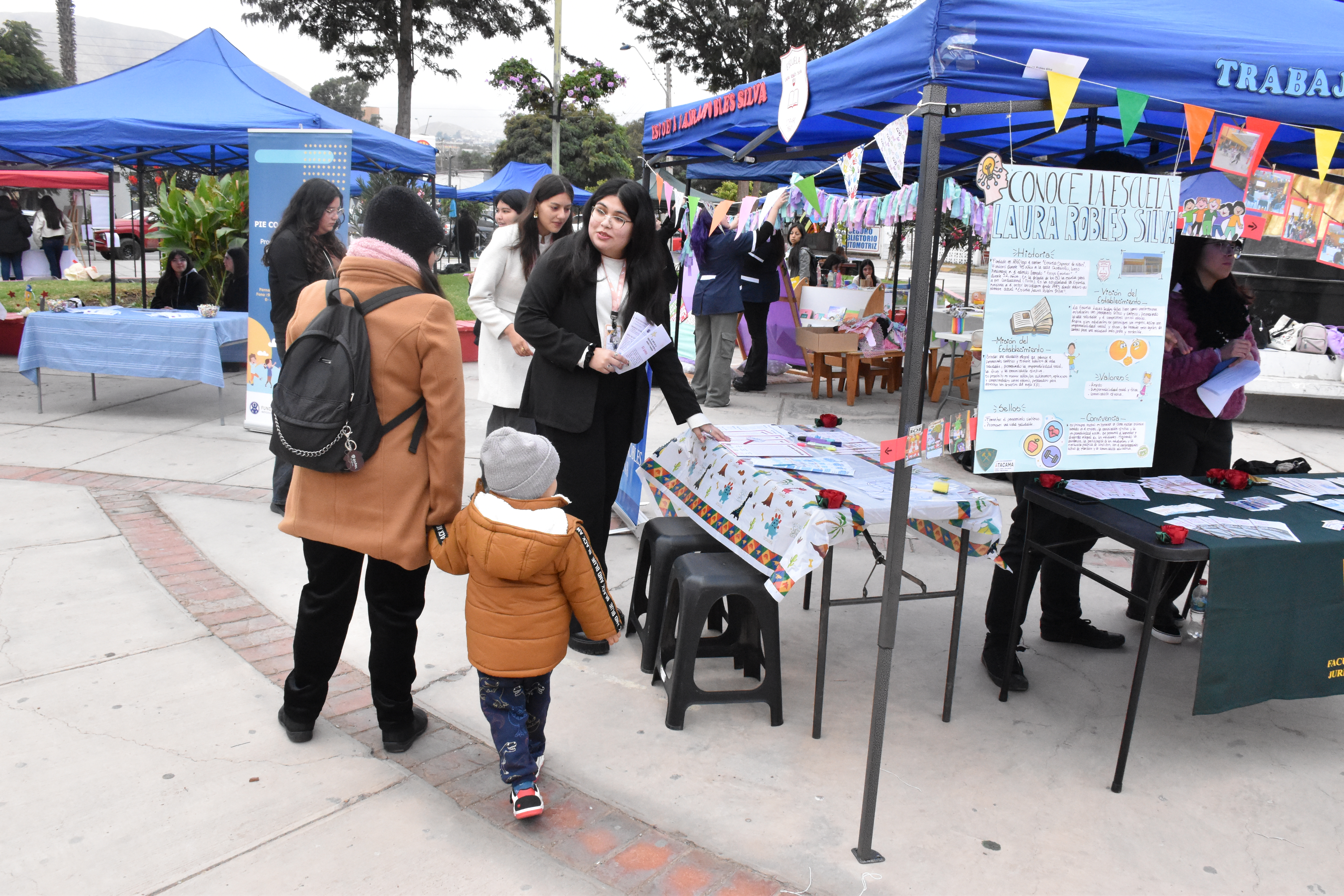 Madre paseando con infante en la Feria Institucional de Prácticas Intermedias de Trabajo Social de la UDA