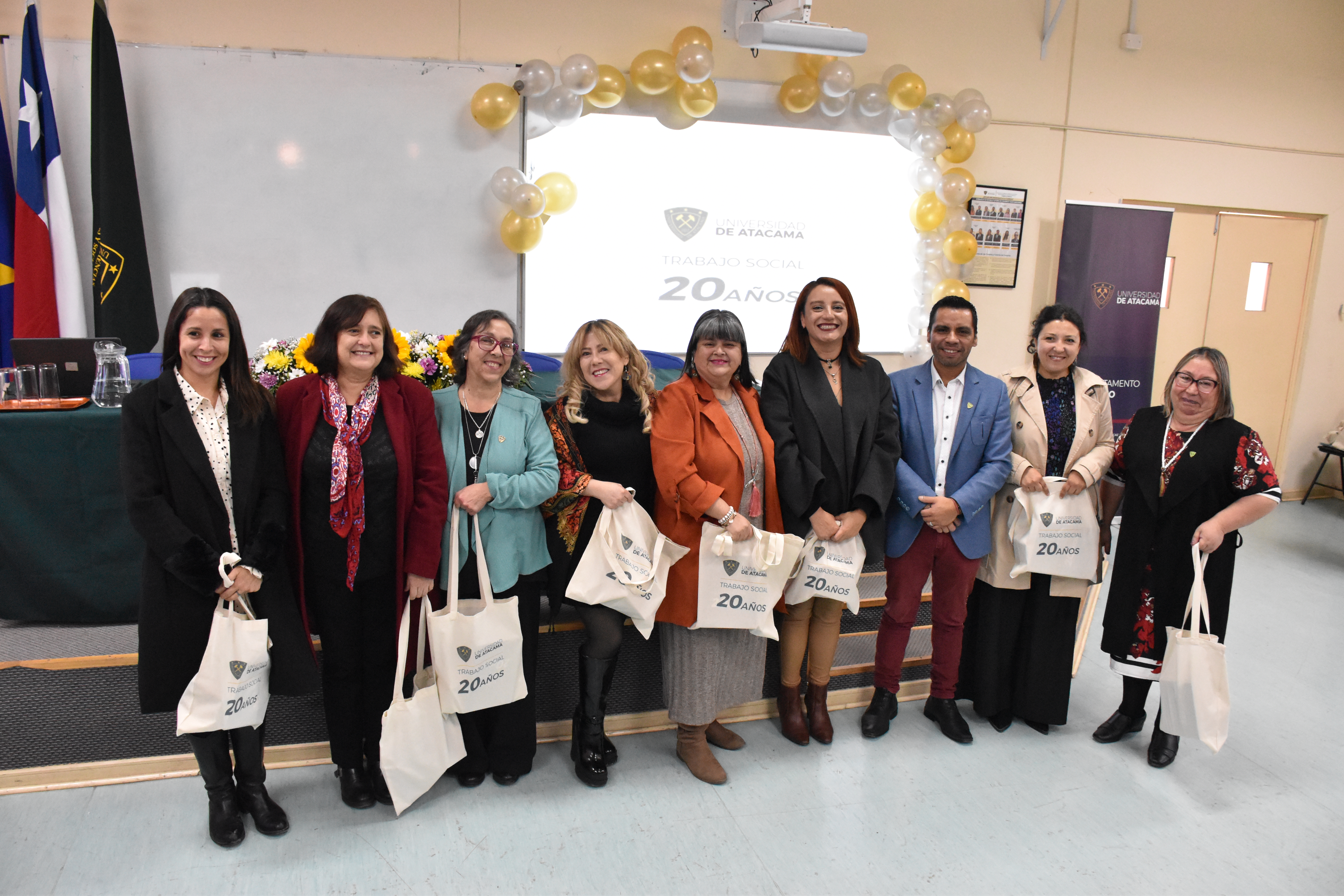 Personas posando de pie para foto en el aniversario de 20 años de trabajo social