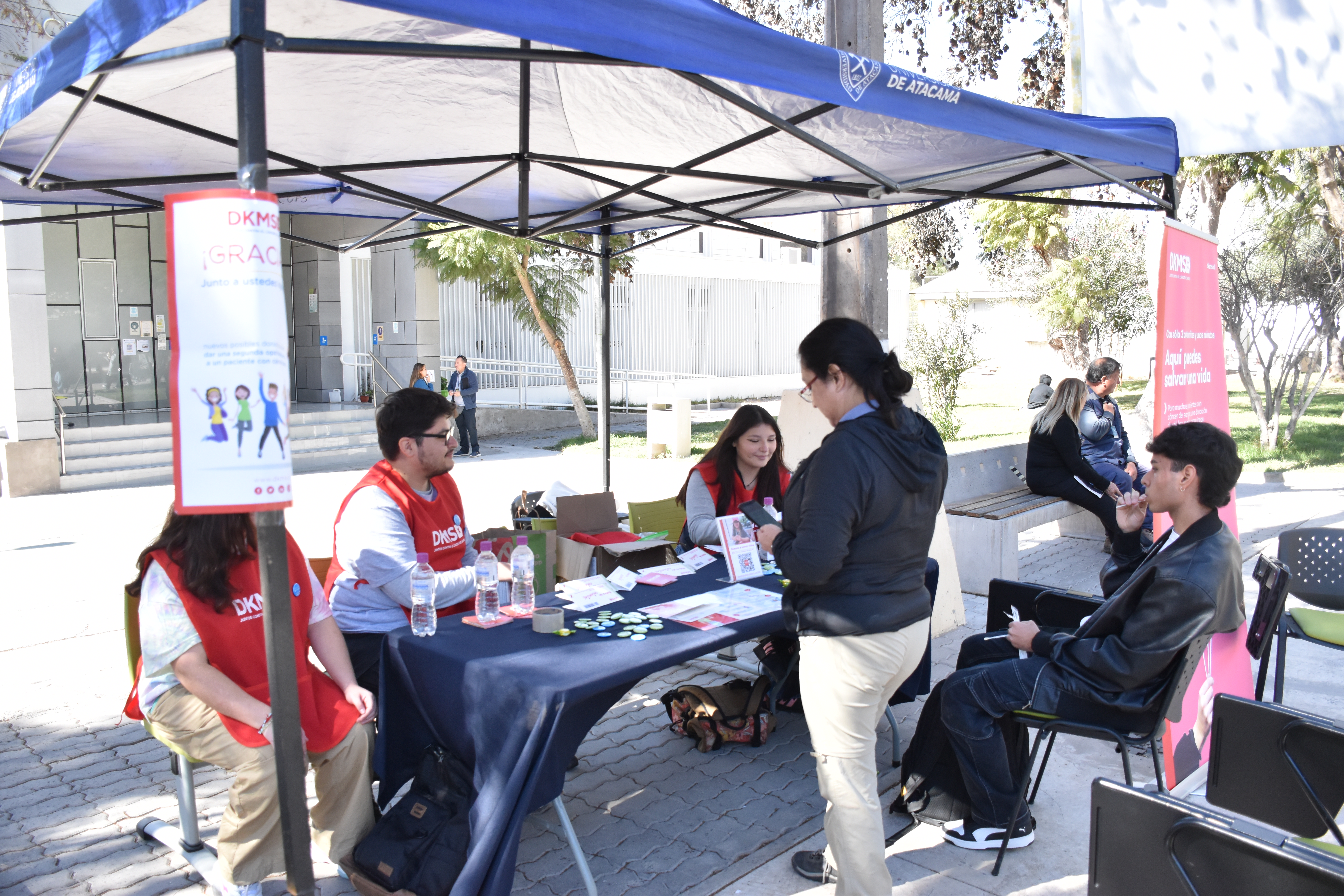 Dos personas registrándose en DKMS en un puesto de tres estudiantes de medicina de la Universidad de Atacama